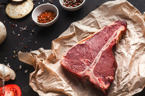 Raw t-bone steak on craft papper on dark background