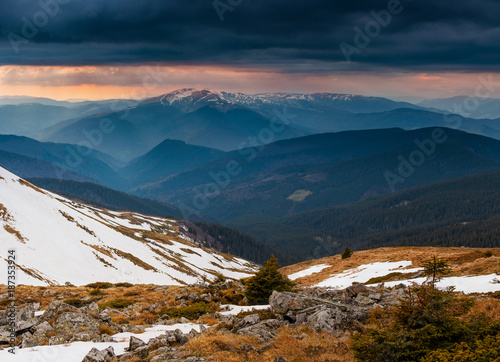 Panorama of idyllic landscape in the spring mountains at sunshine. View of the snow-covered mountain peaks in the distance.