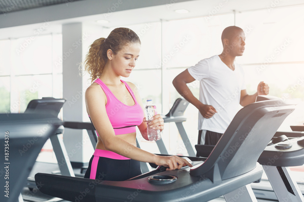 Man and woman, couple in gym on treadmills Man and woman, couple in gym on treadmills