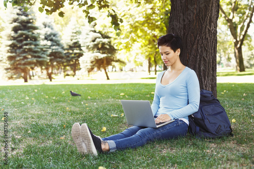 Woman sitting on the grass with laptop outdoors