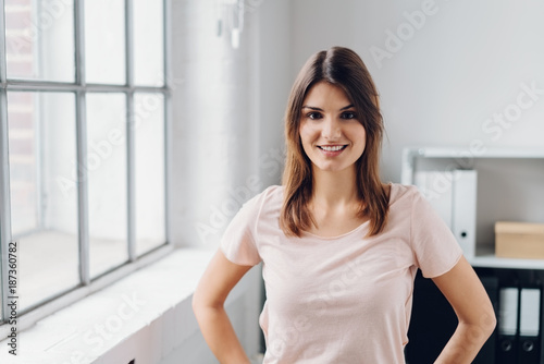 Cheerful young woman standing in office Free Download Cheerful young woman standing in office - GFXLoad