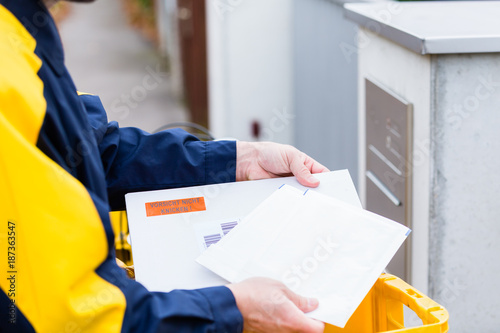 Postman delivering letters to mailbox of a recipient photo