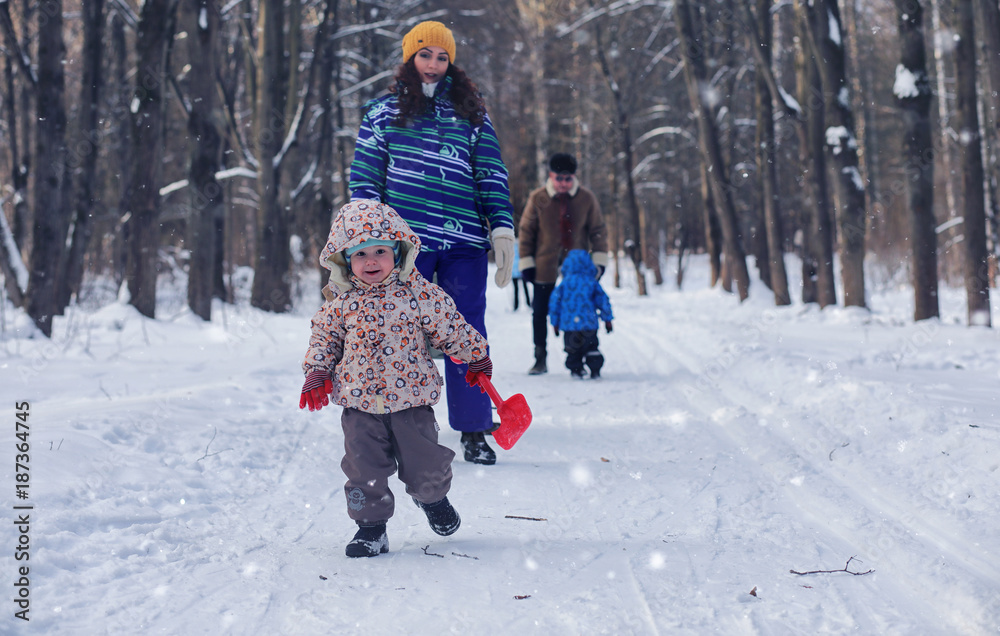 Kid playing in a winter park and have fun with family