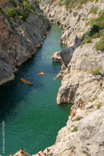Kayaks on turquoise canyong river surrounded by rocks with bathers 