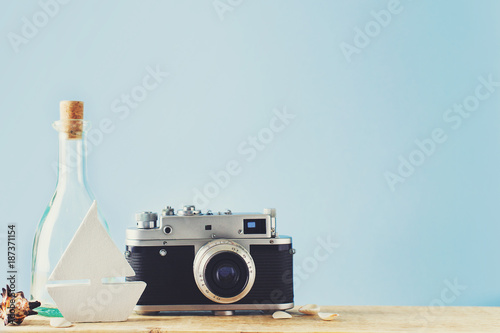 Some elements of vacation theme, camera, botle and toy ship on blue backround