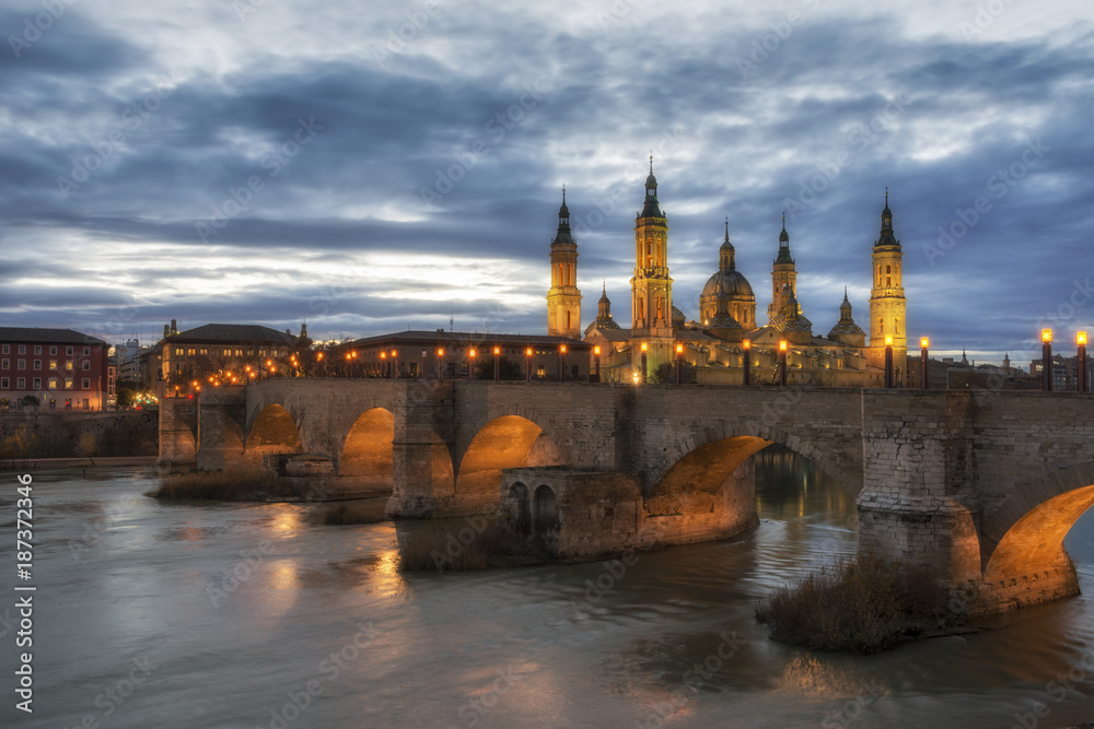 The Cathedral-Basilica and a Stone bridge in Zaragoza on the Ebro River at the night, Spain.
