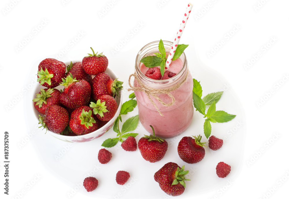 Pink strawberry and raspberry smoothie in a mason jar glass with straw and scattered berries Pink strawberry and raspberry smoothie in a mason jar glass with straw and scattered berries