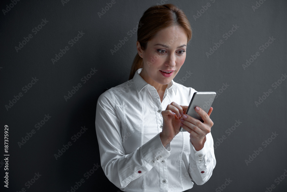 Portrait of surprised female looking at mobile while holding it in hand. Digital device and labor concept Portrait of surprised female looking at mobile while holding it in hand. Digital device and labor concept