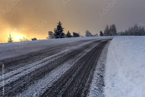 Wintertime - Black Forest. Winter landscape with road covered by snow and sun appearing in the background.