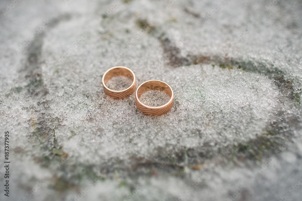 Wedding rings for bride and groom on snow in shape of heart, marriage ...