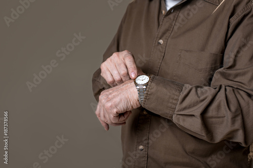 Time is fleeting. close up of wrinkled hand wearing wristwatch. Copy space in left side. Isolated on grey background