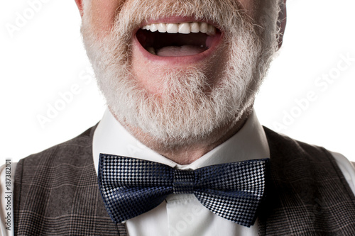 Close up of laughing oldish man with blue bow tied to his neck. Isolated on background
