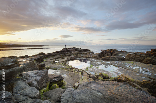 Wallpaper Mural A lone figure on a rocky coast at dusk Torontodigital.ca