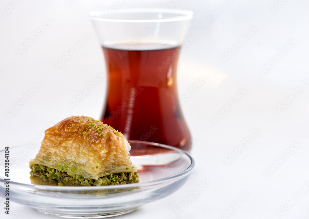 Baklava with pistachio and turkish cup of tea on a white background Baklava with pistachio and turkish cup of tea on a white background