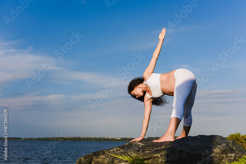 Pregnant woman is practicing yoga beside river