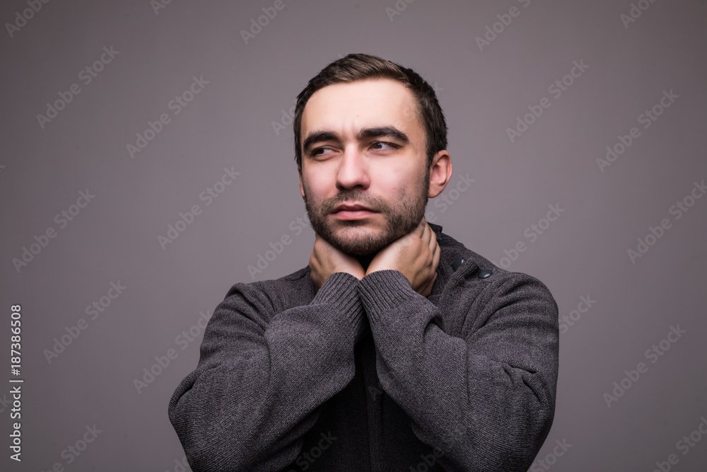 Young man having sore throat and touching his neck against light grey background. Young man having sore throat and touching his neck against light grey background.