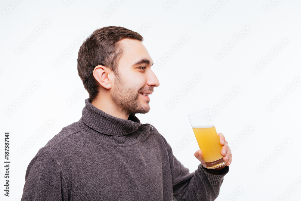 Handsome guy is drinking orange juice on gray background Handsome guy is drinking orange juice on gray background