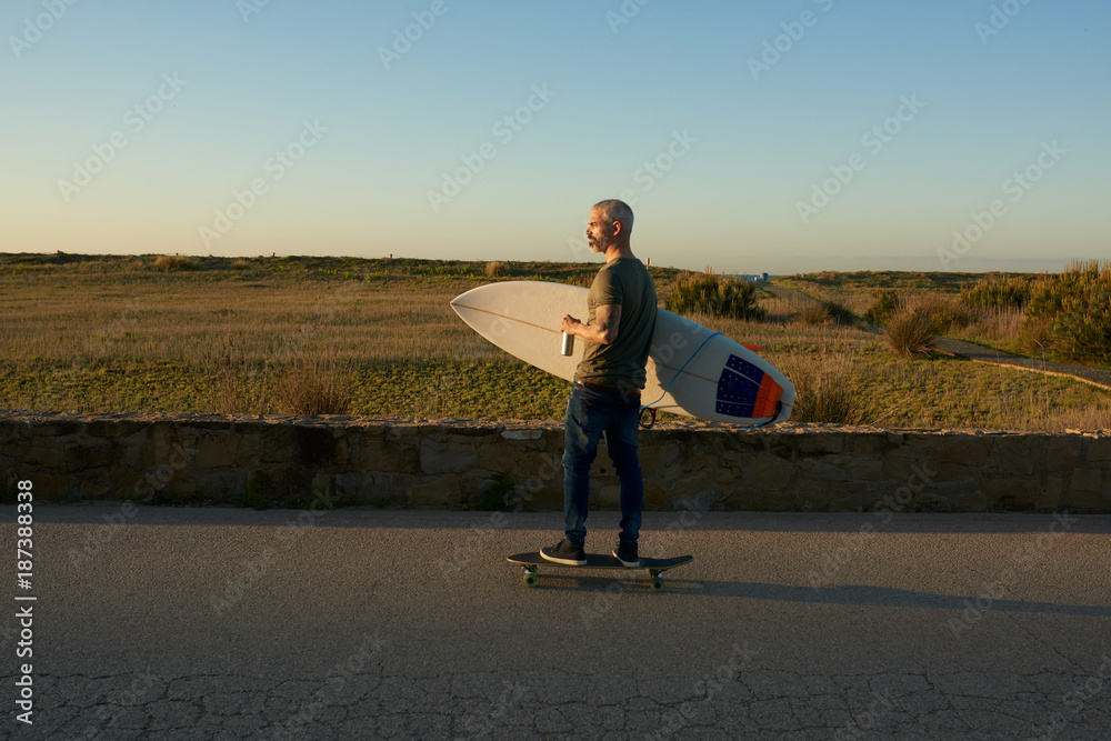 Surfer skating on road with can of drink. Surfer skating on road with can of drink.