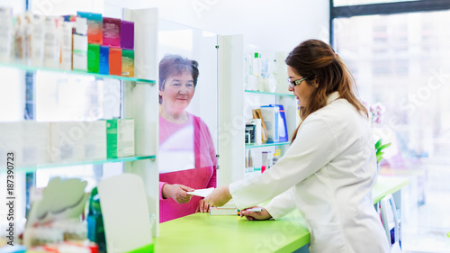 Pharmacist discusses prescription medication with senior customer at pharmacy photo