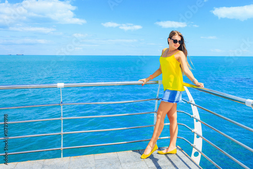 A pretty girl in stylish clothes leaned on a handrail against th
