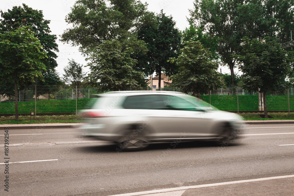 A white car at high speed crosses a pedestrian crossing, a motion blur effect