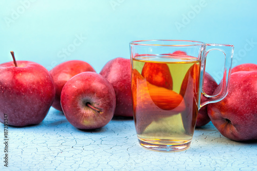 Glass of apple juice and red apples on wooden background . photo