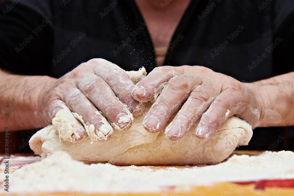 Mens hands knead dough