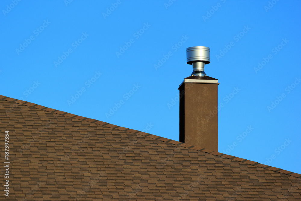 Metal chimney on the roof against blue sky