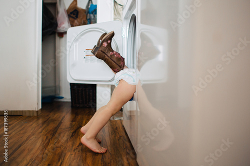 Toddler siblings playing in the dryer and hiding from mom.