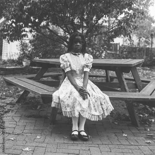 Black girl in a victorian dress sitting at a table