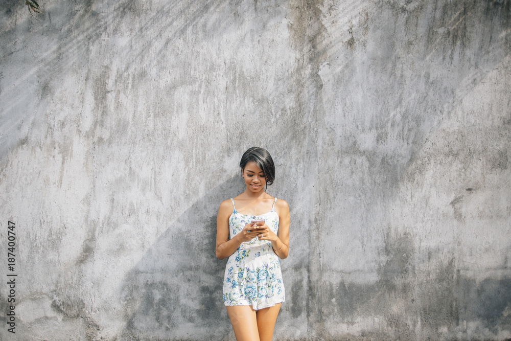 Woman using smartphone on gray rustic wall Woman using smartphone on gray rustic wall