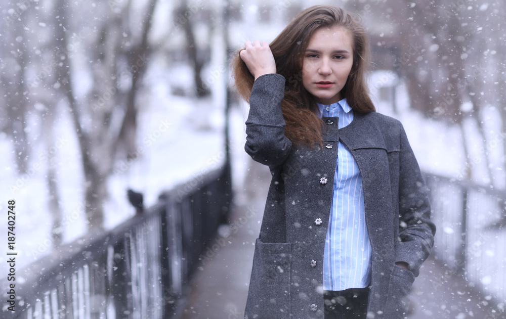 Young girl outdoors in winter. Model girl posing outdoors on a w Young girl outdoors in winter. Model girl posing outdoors on a w
