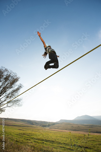 Man jumping on slackline outdoor on a green meadow photo