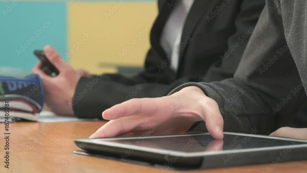 Close-up of hands of two men sits at desk at office. One man holding smartphones other man looking at white-black computer tablet pressing them fingers on screen and look at the important information