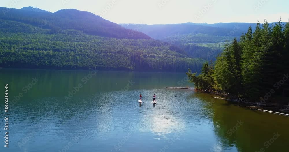 Couple rowing a stand up paddle board in the river Couple rowing a stand up paddle board in the river