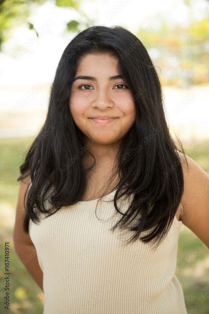 Young Hispanic girl smiling outside.