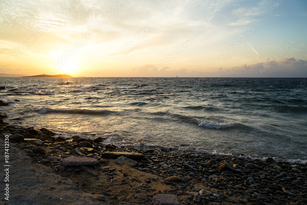 Beautiful sunset scenic copyspace wavy seaview and natural rock beach with shades of orange and blue sky background