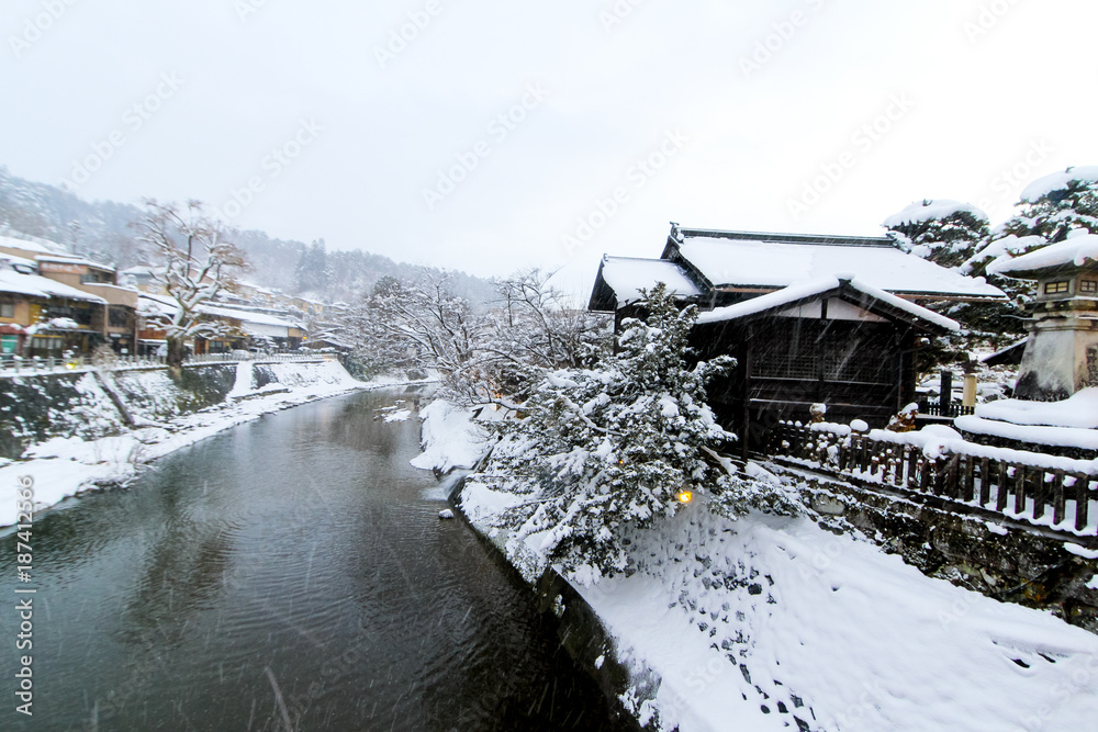 Miyagawa river cover with snow and vintage buildings view looking from red bridge in Takayama view of local Japanese style house near Nakabashi bridge along side