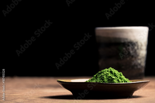 Green tea powder with ceramic cup on the table, black background. Free space for text