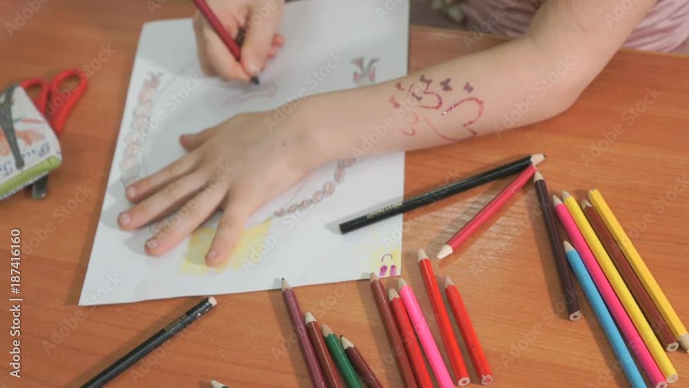 Close-up of unknown little girl draws the pictures using color pencils in the album in the kindergarten Close-up of unknown little girl draws the pictures using color pencils in the album in the kindergarten