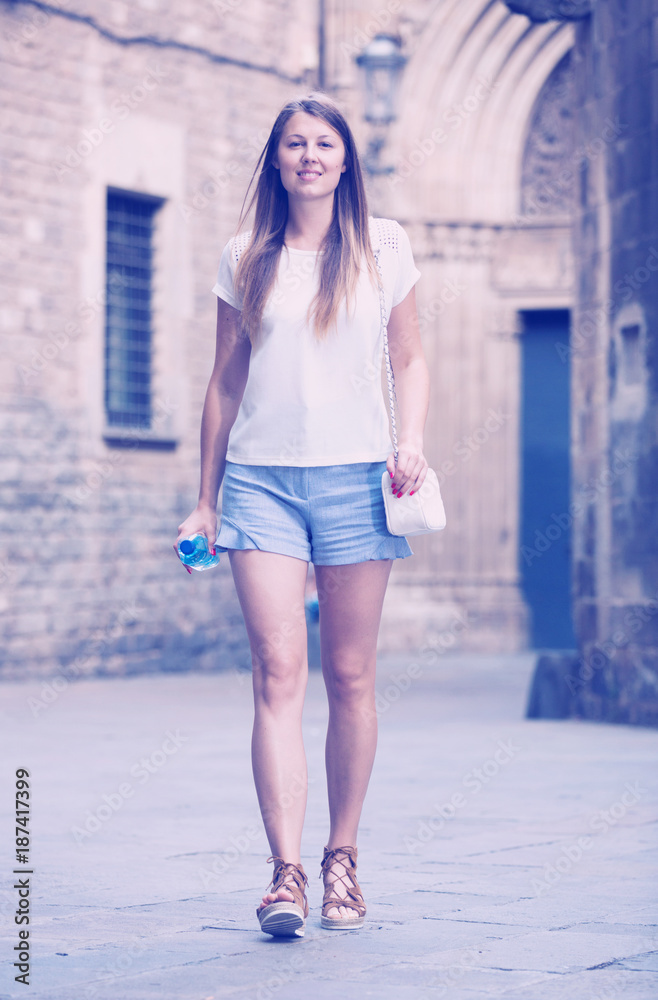 Naklejka premium Woman strolling past old stone castle