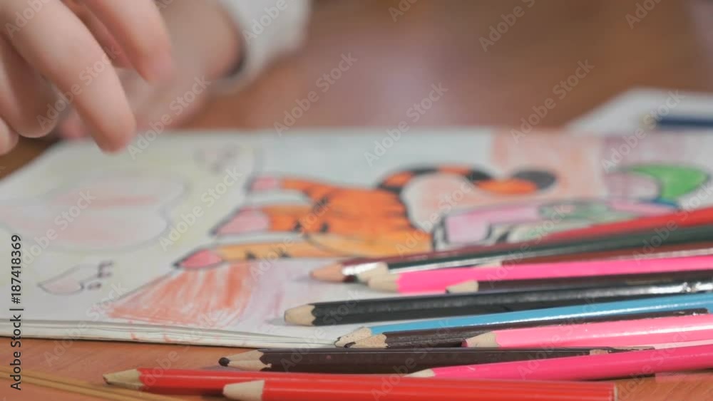 Close-up of unknown little girl draws the pictures using color pencils in the album in the kindergarten Close-up of unknown little girl draws the pictures using color pencils in the album in the kindergarten