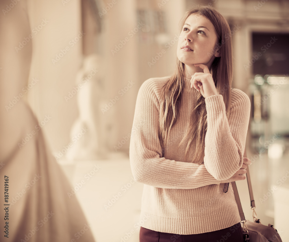 Fototapeta premium Girl looking at ancient sculptures in art museum