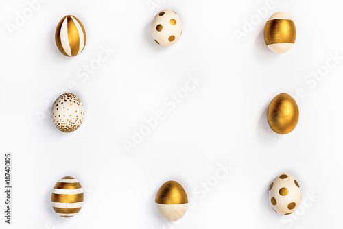 Top view of easter eggs colored with golden paint in differen patterns arranged in square. Various striped and dotted designs. White background. Copy space.