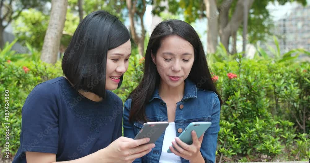 Girl Friends using mobile phone in city together Girl Friends using mobile phone in city together