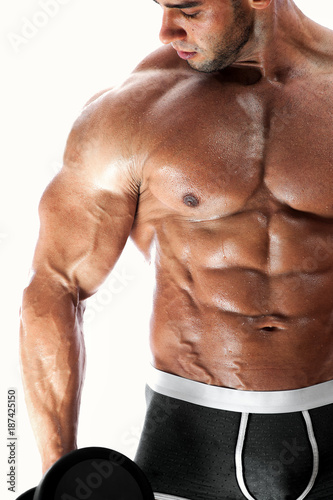 Studio shot of sexy muscular fitness model posing shirtless. Handsome bodybuilder man standing with dumbbell in hand over white background. High resolution