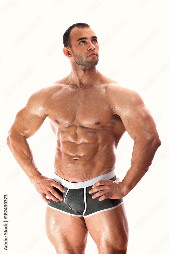 Muscular bodybuilder posing shirtless demonstrating well trained abs, shoulders and chest. Studio shot of middle aged fitness model