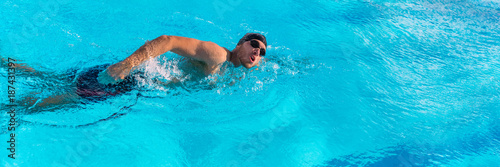 Swim sport athlete swimmer swimming in pool training for race. Professional male watersport adult working out cardio in water at outdoor fitness stadium. Banner panoramic crop.
