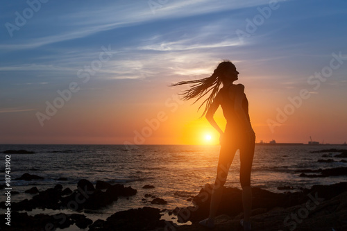 Silhouette of flexible girl with dreadlocks on ocean coast during amazing sunset. © De Visu