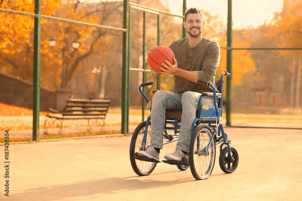 Young man in wheelchair with ball on playground